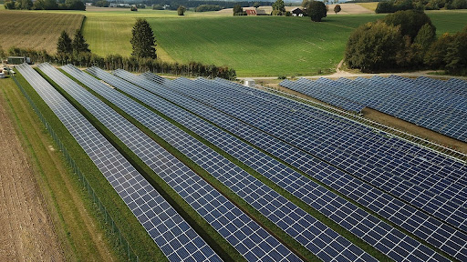 A solar farm surrounded by green fields and a few trees