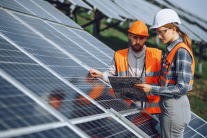 Two technicians next to a ground mounted solar panel