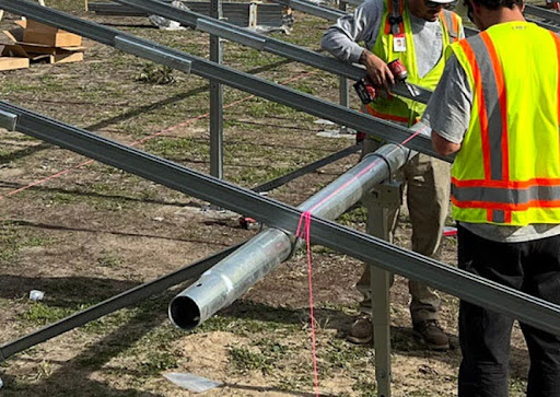 Two men in safety vests working on the installation of a ground-mount solar system.